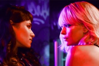Charlize Theron e Sofia Boutella em cena do filme Atômica (2017), olhando-se fixamente em um ambiente com iluminação neon.