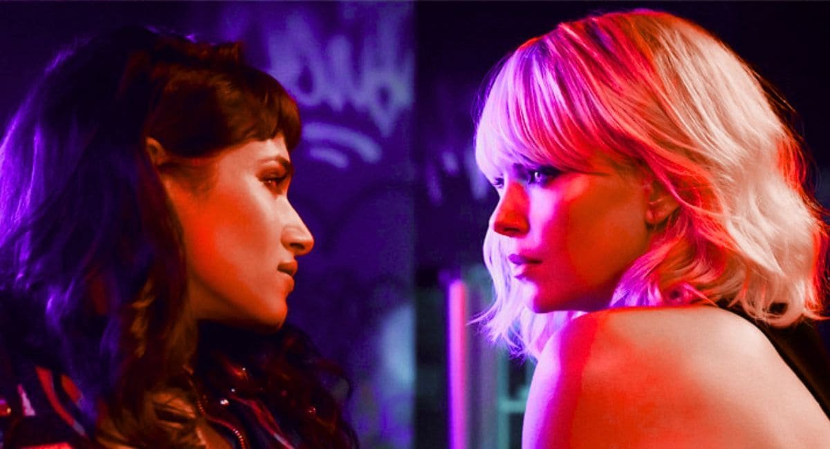 Charlize Theron e Sofia Boutella em cena do filme Atômica (2017), olhando-se fixamente em um ambiente com iluminação neon.