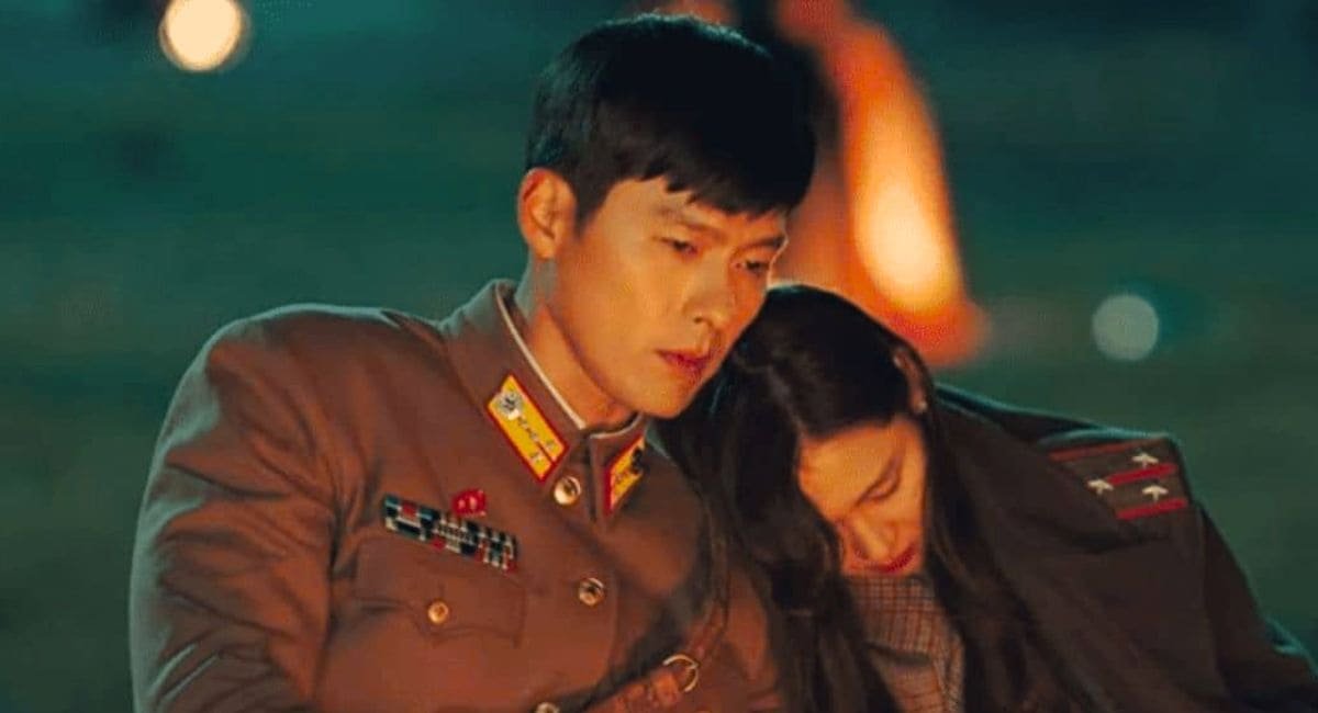 Os atores Hyun Bin e Son Ye-jin fardados em cena de Pousando no Amor, destacando o uniforme militar norte-coreano e o clima de romance.